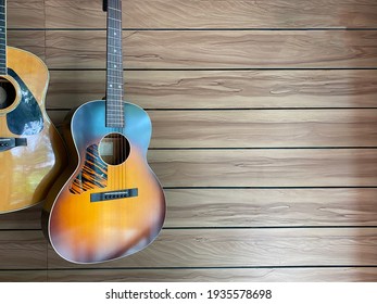 à¸·natural and sunburst Two acoustic guitars hung on a brown ash wood grain wall in a music shop with copy space on the right hand for text.music or coffee shop concept.