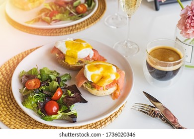 Sunday brunch with eggs benedict, salad and coffee on white table close-up
