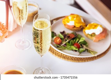 Sunday Brunch With Prosecco And Eggs Benedict On White Table Close-up