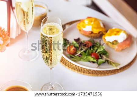 Sunday brunch with prosecco and eggs benedict on white table close-up
