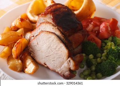 Sunday roast of baked pork with vegetables and Yorkshire pudding close-up, horizontal