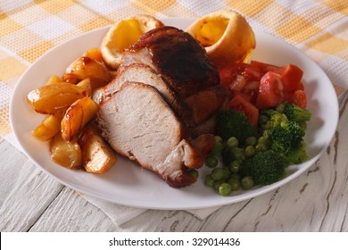 Sunday Roast: Pork With Potatoes, Vegetables And Yorkshire Pudding On The Plate Closeup. Horizontal
