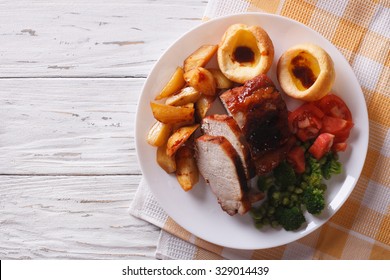 Sunday Roast: pork with potatoes, vegetables and Yorkshire pudding close up on the table. horizontal view from above