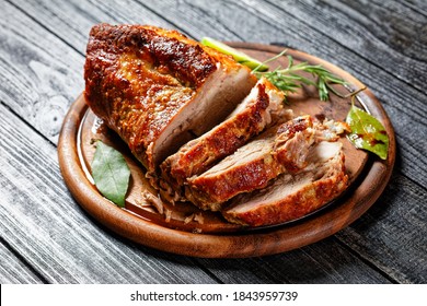 Sunday roasted pork tenderloin, juicy and succulent oven-baked piece of meat rubbed with mustard and spices: rosemary, bay leaf, lime juice, and pepper on a wooden background, close-up, top view - Shutterstock ID 1843959739