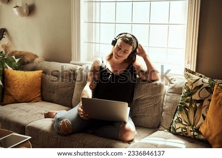 Sundays are for marathon movie streaming sessions. Shot of a young woman using a laptop and headphones on the sofa at home.