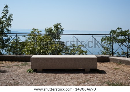A sun-drenched bench sits on an elevated panoramic point on the via Napoleonica in Trieste, Italy