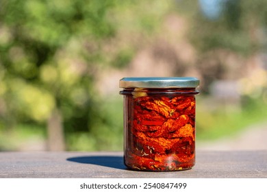 Sun-dried red tomato with garlic, rosemary, olive oil and spices in a glass jar on a wooden table. Rustic style, close up - Powered by Shutterstock