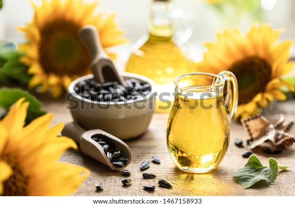Sunflower oil in a bottle glass with\
seeds and flowers of sunflower. on blurred\
background