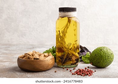 Sunflower oil in a glass jar with various herbs and spices, sesame, rosemary, avocado, basil, almond on a brown concrete background. Side view, copy space. - Powered by Shutterstock