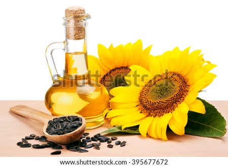 Sunflower oil, spoon with seeds and flowers lays on wooden table 