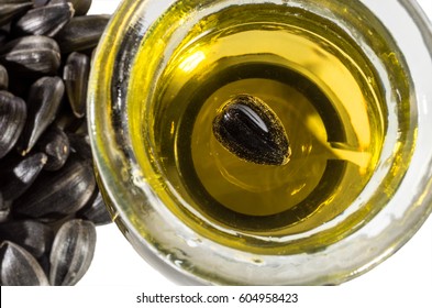 Sunflower Seed Floating In The Sunflower Oil In A Round Bowl On A Background Of A Bunch Of Blurry Sunflower Seeds. Selective Focus.