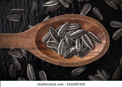 Sunflower Seeds Overhead Large Organic Roasted And Salted Close-up Macro Photography Arrangement In Old Wooden Spoon On Black Shiny Stone Background In Studio