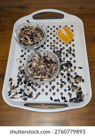 Sunflower Shells And Dried Orange Slice On White Tray With Two Glass Bowls, Scattered Sunflower Seeds And Husks, Warm Wood Table Backdrop, Rustic Autumn Mood,
