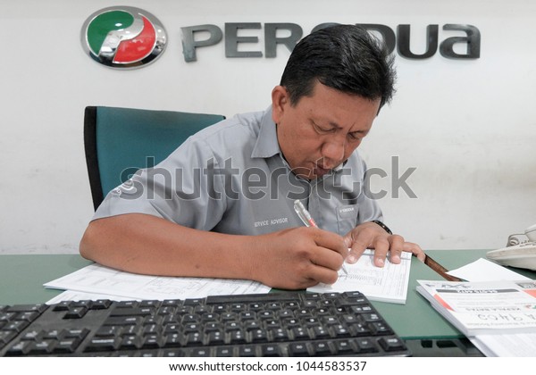 Sungai Petani,KEDAH - FEBRUARY 12TH 2018 : staff\
reviewed the list of services to create a car service to customers\
in Perodua Service\
Center.