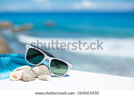 sunglasses lying on tropical sand beach. party. white towel on desk and red glasses with seashells. Sunglasses on the beach. Beautiful sea view wallpaper, background