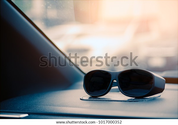 Sunglasses on\
the front console in the car and have lake morning light on front\
mirror in vacation or traveling\
day.