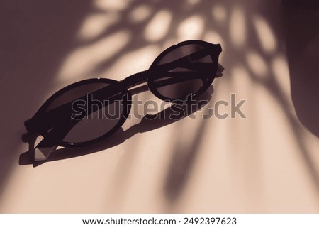 Sunglasses on a white table. Stylish summer accessories. Sunglasses on a white table. In the shadow from sunlight. Fashion magazine cover. Sun protection. How to hide your face. Refined taste.