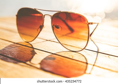 Sunglasses on a wooden table and rays of sunlight
