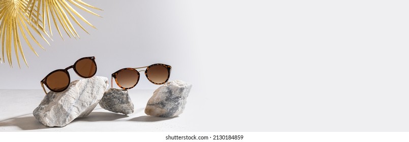 Sunglasses sale banner. Summer sale-out offer. Trendy sunglasses in plastic frame on a light background with golden palm leaf. Copy space for text. For banner, web line. Optic store discount