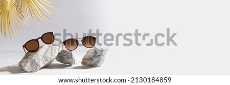 Sunglasses sale banner. Summer sale-out offer. Trendy sunglasses in plastic frame on a light background with golden palm leaf. Copy space for text. For banner, web line. Optic store discount