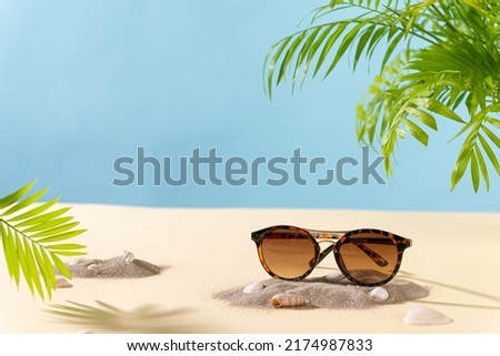 Sunglasses sale concept. Trendy sunglasses on beach with green palm leaves. Trendy Fashion summer accessories. Side view, copy space. Optic store. Vacation, travel concept. Sunglass offer banner