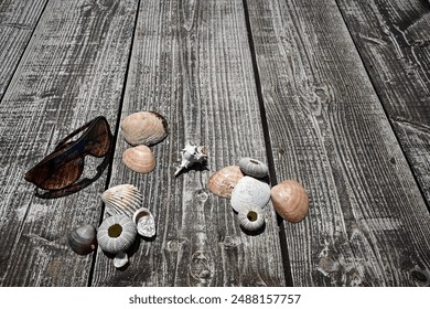 Sunglasses and seashells lying on a rustic wooden surface, evoking summer holiday memories.