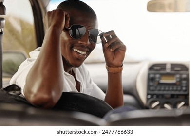 Sunglasses, travel and black man with smile in car for outdoor adventure, holiday and summer journey. Relax, male person and happy with drive in vehicle for road trip, vacation or tourism in Kenya - Powered by Shutterstock