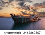 Sunken cargo ship lying on its side at sunset in Aliaga Bay, Izmir.