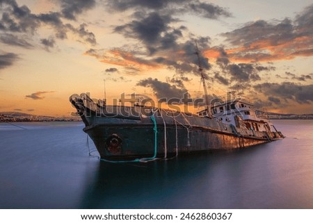 Sunken cargo ship lying on its side at sunset in Aliaga Bay, Izmir.