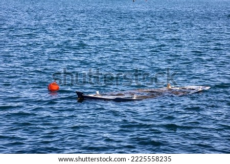 Sunken fishing boat with red buoy close up, sea view. Safety and accident insurance concept. Copy space