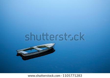 sunken rowboat in a quiet blue lake