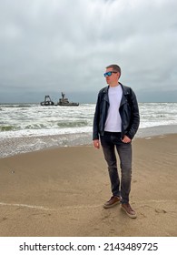 Sunken Trawler, Shipwreck. A Stranded Ship. Old Rusty Metal Ship. Zeila At The Skeleton Coast In Namibia. Atlantic Ocean Off The Coast Of Africa. Man Stands And Looks At The Beach.