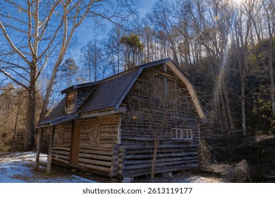 Sunlight beems down over a hillside where an old log cabin sits along side a rode in the Great Smoky Mountains in North Carolina, USA