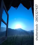 Sunlight, a blue sky and clouds, can be seen through the window, overlooking the rice fields. In the rice paddy area, bamboo stakes are planted in the ground to support the peanut plants. The rural atmosphere is natural and serene. 
