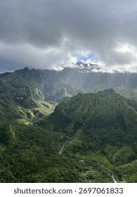 Sunlight Breaking Through Clouds Over Lush Green Mountains