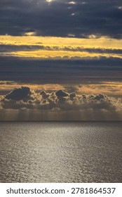 Sunlight breaking through clouds over the ocean at sunset