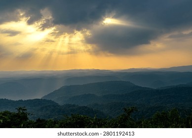Sunlight breaking through clouds over the lush forest and hills of Kali Tiger Reserve, Dandeli, Karnataka, India.