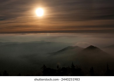 The sunlight is breaking through the clouds in the sky, creating a beautiful afterglow over the mountains and horizon, a stunning atmospheric phenomenon in the natural landscape