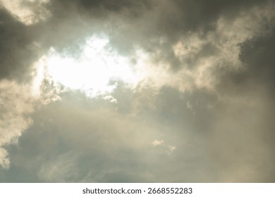 Sunlight is breaking through dark clouds, creating a dramatic and beautiful sky background