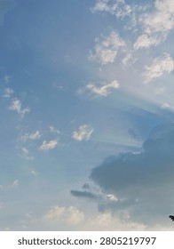 Sunlight breaking through fluffy white clouds in a blue sky