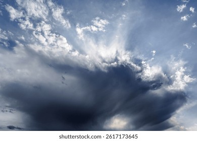 Sunlight breaks through thunder clouds in dramatic blue skyDramatic Sky Background.