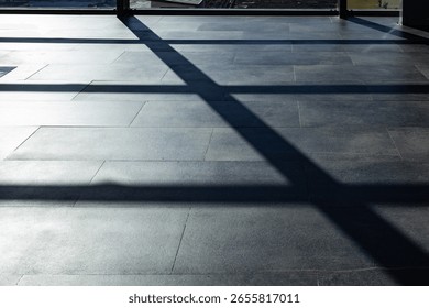 Sunlight casts geometric shadows of window frames on a polished airport floor, creating a minimalistic pattern.