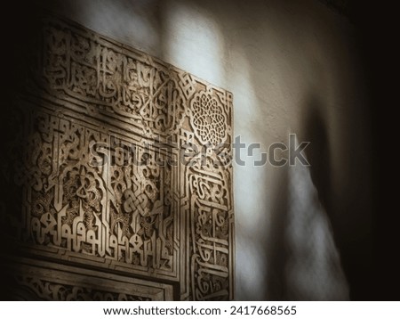 Sunlight coming through an engraved window of a famous Arabian palace of Alhambra in Andalusia, throwing light and shadow on the engraved walls
