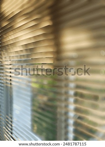 the sunlight creates patterns of light and shadow on the blinds