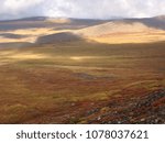 Sunlight dramatically breaks through a storm on the Canadian arctic in the Fall. Dempster Highway, Yukon Territory, Canada.
