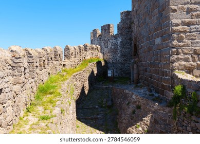 Sunlight glints off the ancient stone battlements and winding paths of Mithymna Castle in Molyvos on Lesbos, showcasing the impressive and historic medieval architectures in Greece.