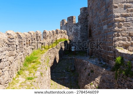 Sunlight glints off the ancient stone battlements and winding paths of Mithymna Castle in Molyvos on Lesbos, showcasing the impressive and historic medieval architectures in Greece.