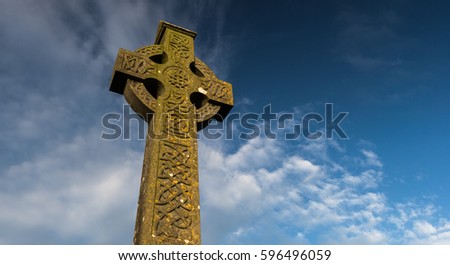 Sunlight hitting celtic cross gravestone at dawn