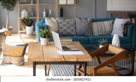 陽光照亮起居室工作場所家庭辦公室內部，舒適的高效工作，棕色和藍色。在木桌上的筆記本電腦舒適的沙發上，背景靠墊，工作日結束概念