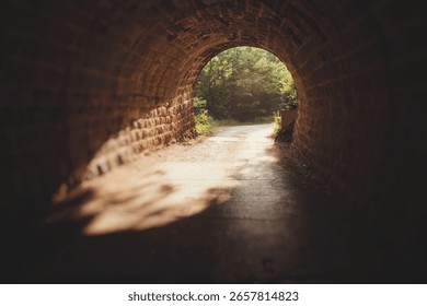 Sunlight illuminates the path at the end of a dark stone tunnel, symbolizing hope and new beginnings